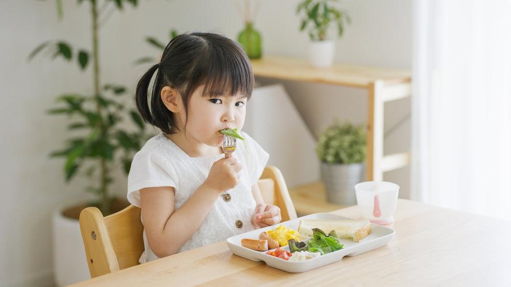 食卓に並んだ幼児食を前に座る2歳ごろの子ども