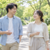 緑の多い公園を、会話しながら並んで散歩する男女