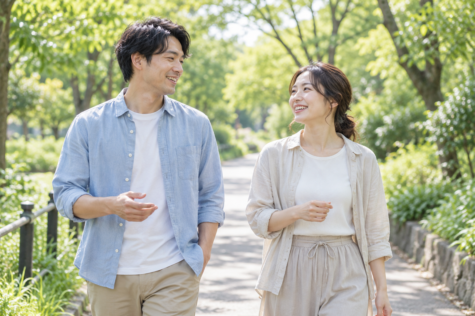 緑の多い公園を、会話しながら並んで散歩する男女
