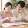 自宅のテーブルで、手帳と書類を一緒に確認する男女