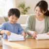 5歳ごろの男の子が母親と並んでタオルをたたんでいる