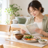 食事と水を用意したテーブルで妊娠中の記録を読む女性のイメージ