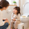 トイレのそばで、ぬいぐるみを持つ3歳ごろの子どもに優しく話しかける母親