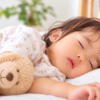 やさしい明かりの寝室で、気持ちよさそうに眠っている1歳くらいの女の子