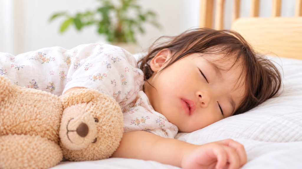 やさしい明かりの寝室で、気持ちよさそうに眠っている1歳くらいの女の子