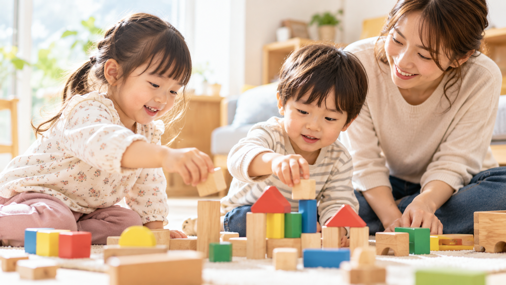 積み木で一緒に遊ぶ3歳ごろの女の子と男の子を、そばで優しく見守る大人