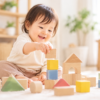 明るい室内で積み木を重ねて遊ぶ生後11か月ごろの赤ちゃん
