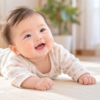やわらかな自然光の中で、うつぶせになり笑顔を見せる生後5か月ごろの赤ちゃん