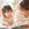 絵本を見ながら笑顔でやり取りする2歳の子どもと母親